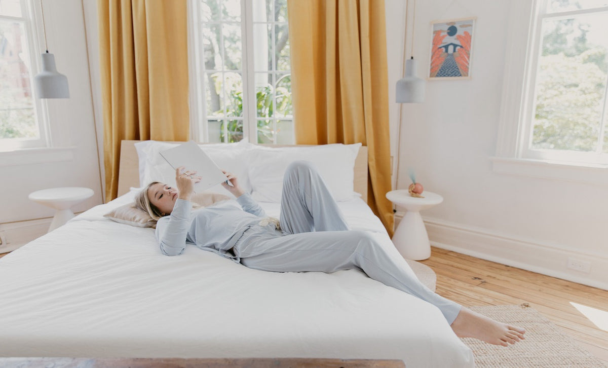 Womain in grey joggers lying on the bed, reading